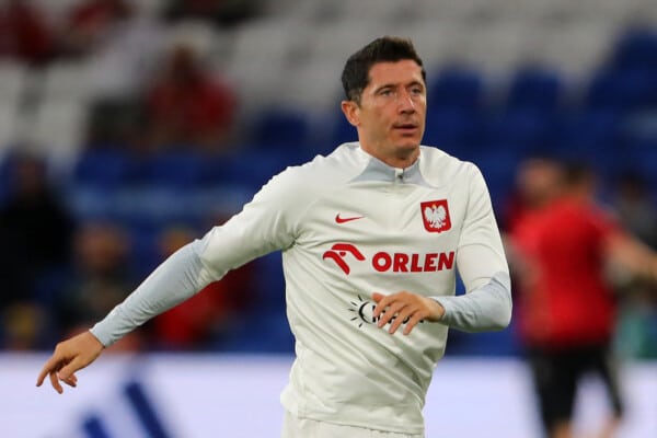 Robert Lewandowski rozgrzewa się w koszulce treningowej reprezentacji Polski z długim rękawem i napisami sponosrów m.in. Orlenu.