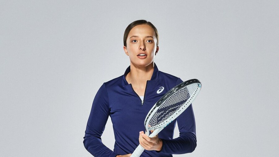Iga Świątek w ciemnoniebieskim stroju z rakietą tenisową w dłoni.