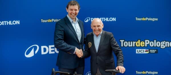 Przedstawiciel Decathlonu oraz Tour De Pologne pozują na ściance, ściskając sobie dłonie