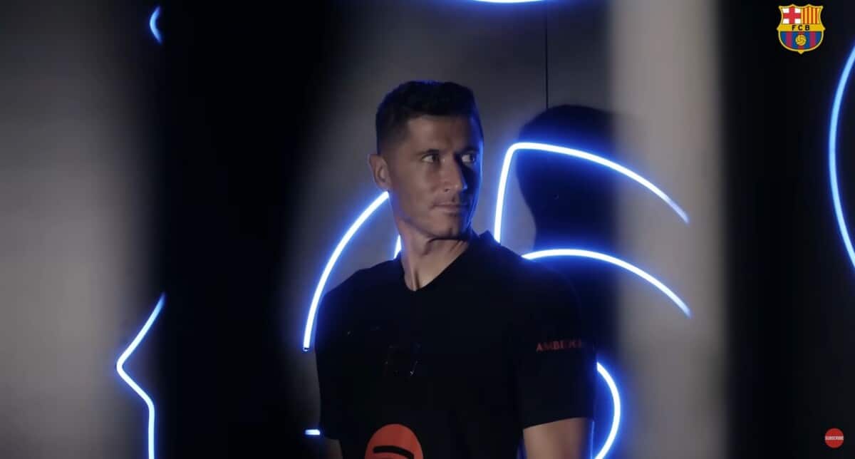 Robert Lewandowski pozuje na tle czarnej ściany, na której znajdują się światła LED