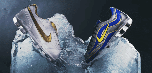Dwie sportowe buty Nike, jedna w białej kolorystyce ze złotym logo, druga w niebiesko-czarnej kolorystyce z żółtym logo, zatopione w dużej bryle lodu na ciemnym tle.