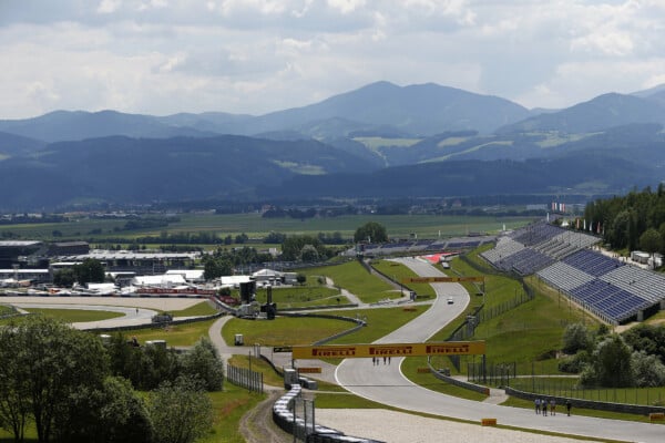Widok na tor wyścigowy Red Bull Ring w Austrii z trybunami, otoczony zielonymi wzgórzami i górami w tle