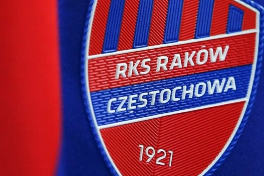Herb Rakowa Częstochowa w kształcie tarczy, w czerwono-niebieskich barwach, z białym napisem „RKS Raków Częstochowa 1921”.