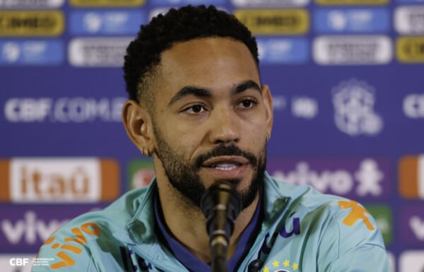 Matheus Cunha podczas konferencji prasowej w stroju reprezentacji Brazylii, na tle sponsorów i logo CBF, po ogłoszeniu transferu do Manchesteru United