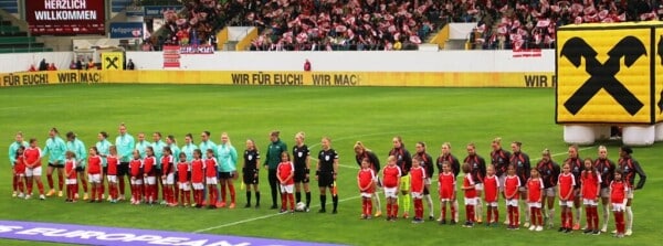 Drużyny Austrii i Islandii wraz z dziećmi podczas prezentacji przed meczem eliminacji UEFA Women’s Euro 2025 na Stadionie Austria Wien, kibice z flagami w tle