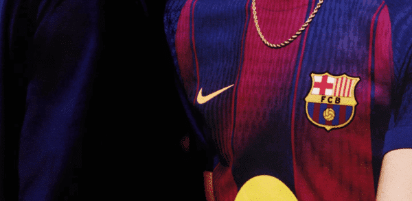 Fragment koszulki piłkarskiej FC Barcelona z wyraźnym herbem klubu i logo Nike, przedstawiony z bliska.