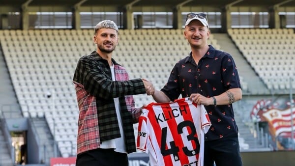 Mateusz Klich przekazuje koszulkę Cracovii Parisowi Platynovowi podczas oficjalnej prezentacji transferu na stadionie w 2025 roku