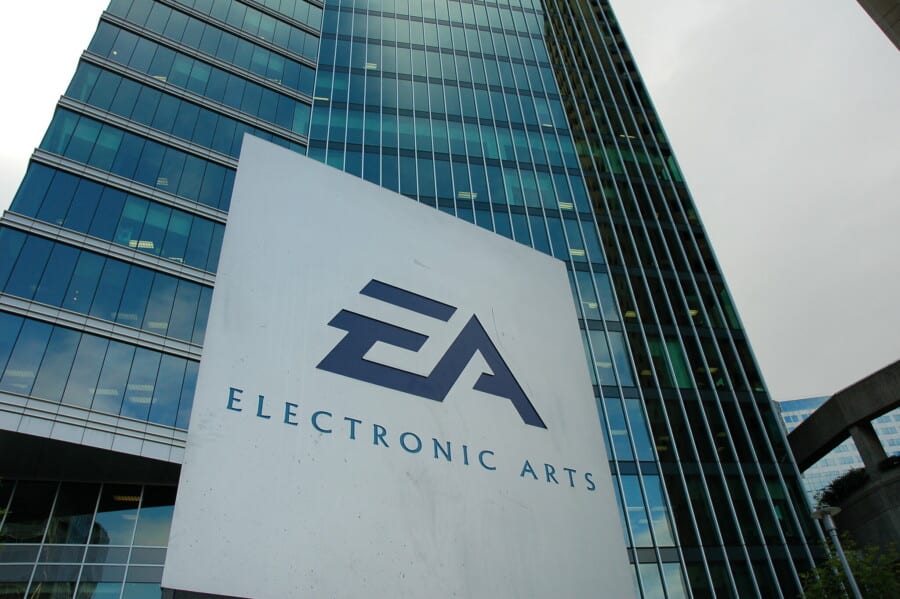 Logo Electronic Arts przed nowoczesnym biurowcem firmy EA z przeszkloną fasadą.