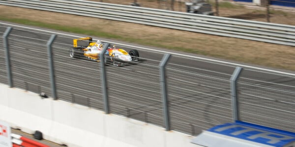 Bolid Formuły 3 na torze wyścigowym podczas wyścigu, widok z trybun, dynamiczne ujęcie motorsportu.