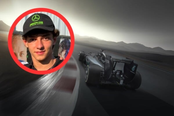 Członek Mercedes AMG Petronas Junior Team w czapce zespołu, stojący przed plakatem, z bolidem Formuły 1 jadącym po torze w tle