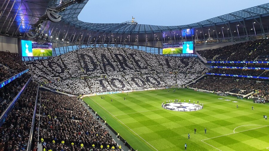 Widok na South Stand stadionu Tottenham Hotspur podczas meczu Ligi Mistrzów UEFA, kibice tworzą napisy 'DARE TO DO' efektowną choreografią na trybunach