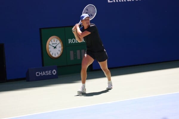 Tenisistka wykonuje zamaszysty backhand na twardym korcie US Open, w tle widoczne logo Rolex oraz Chase