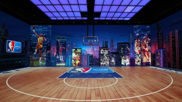 Nowoczesne boisko do koszykówki z logotypami NBA i Prime Video oraz muralami legendarnych graczy NBA na tle panoramy miasta