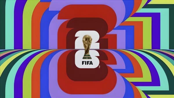 Kolorowa grafika z oficjalnym logo Mistrzostw Świata FIFA 2026, z centralnie umieszczonym pucharem świata na tle abstrakcyjnych, wielobarwnych kształtów.