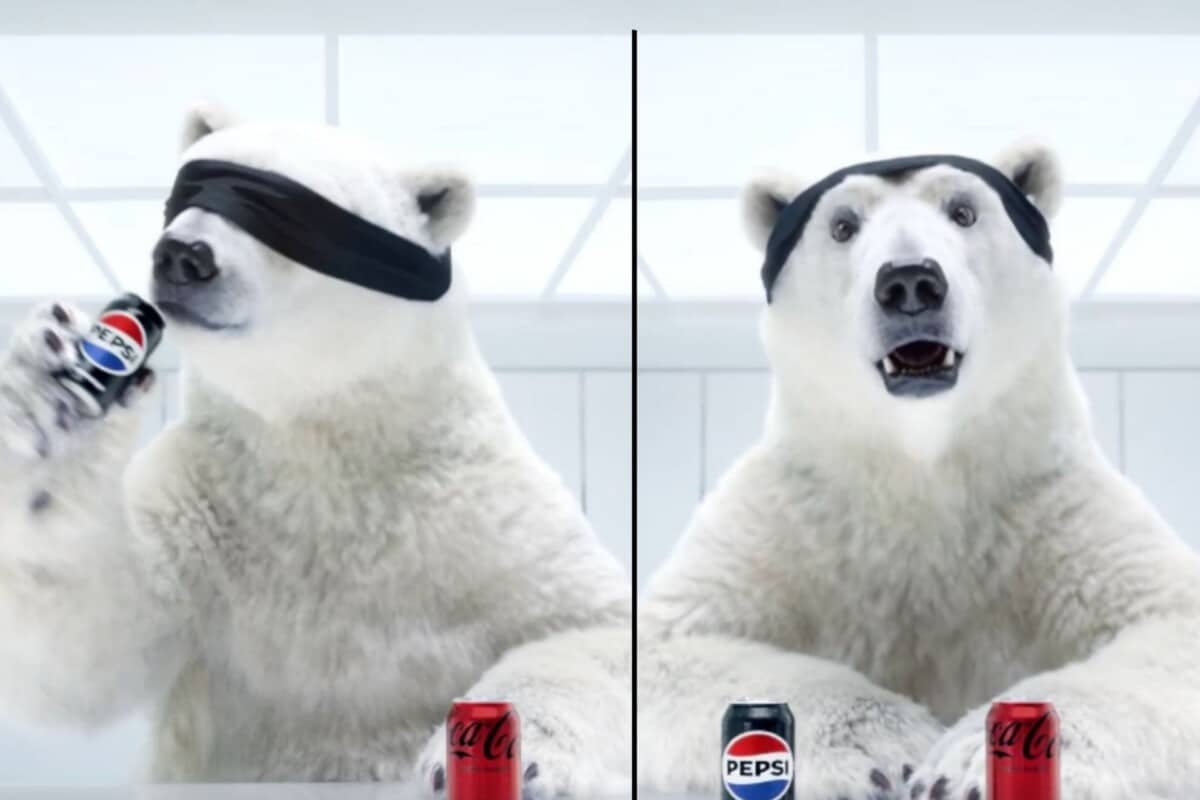 Biały niedźwiedź w czarnej czapce trzymający puszkę Pepsi z entuzjastycznym wyrazem twarzy, obok puszek Coca-Cola i Pepsi - zabawna reklama o wyborze napoju z okazji Super Bowl