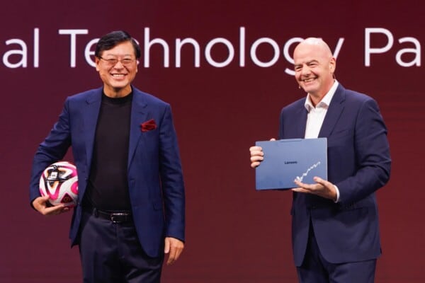 Prezes FIFA Gianni Infantino i prezes Lenovo Yuanqing Yang trzymają piłkę i laptop na scenie Lenovo Tech World @ CES 2026 z logo FIFA World Cup 2026 – ogłoszenie innowacji AI dla MŚ 2026