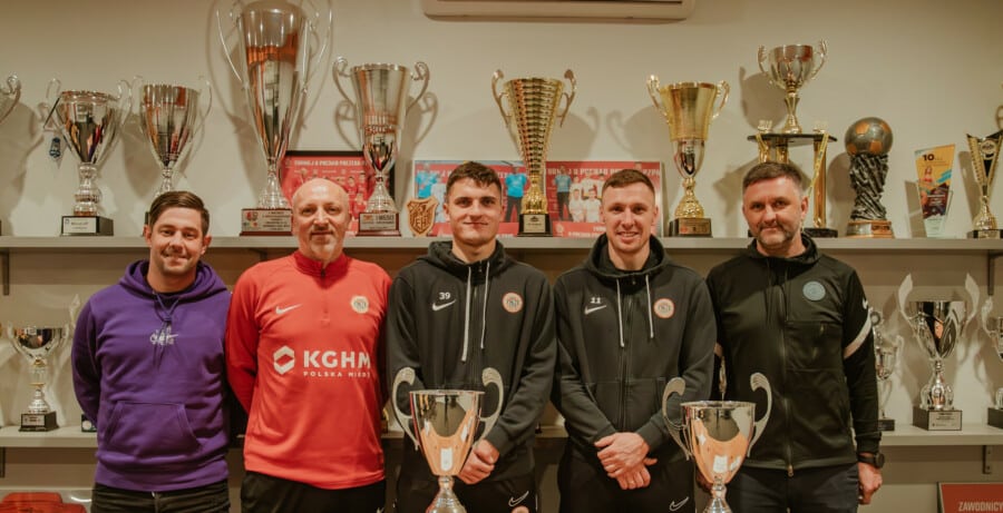 Trenerzy Akademii KGHM Zagłębie Lubin z pucharami KGHM Talent Cup 2026 przed szafą trofeów, Damian Dąbrowski, Krzysztof Paluszek i inni