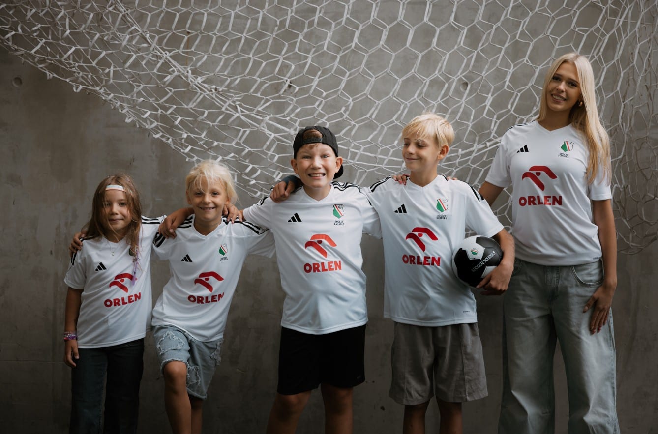 Dzieci z Legia Soccer Schools w koszulkach z logo ORLEN na boisku piłkarskim