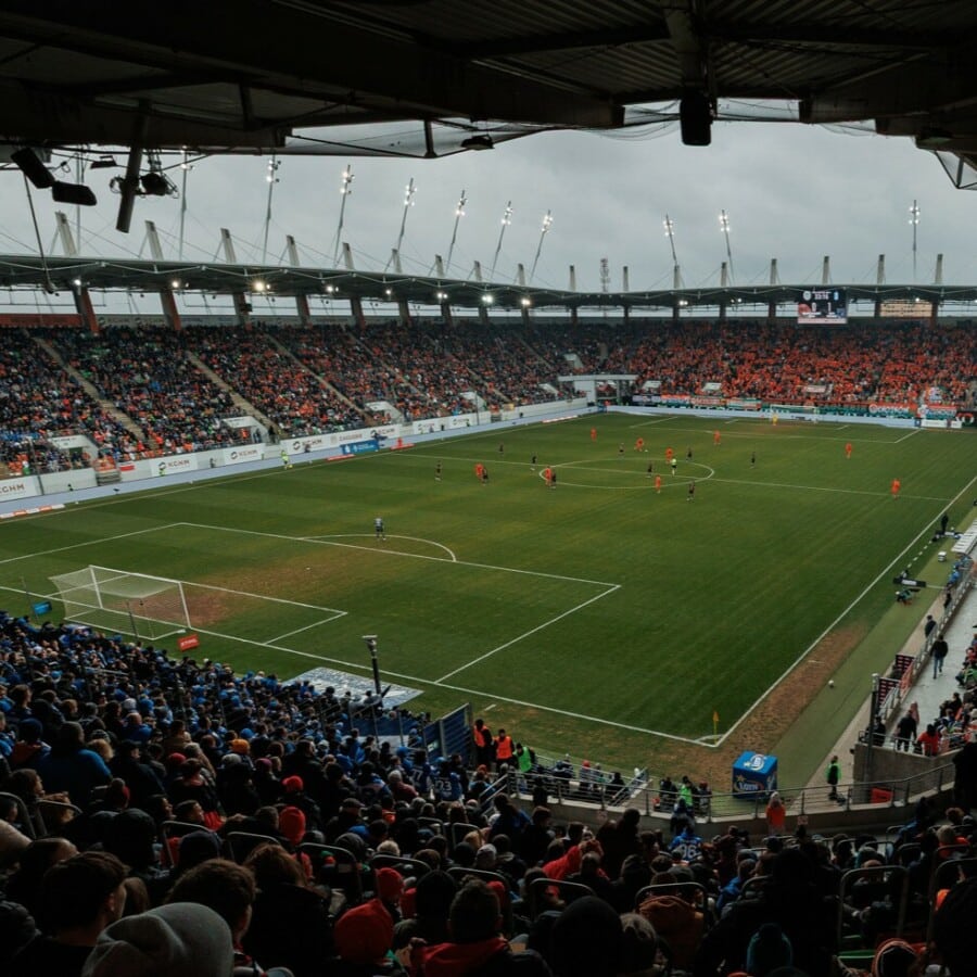 Widok z lotu ptaka na pełny stadion KGHM Zagłębie Arena w Lubinie podczas meczu z rekordową frekwencją kibiców Zagłębia, otoczony pomarańczowymi trybunami i zieloną murawą.