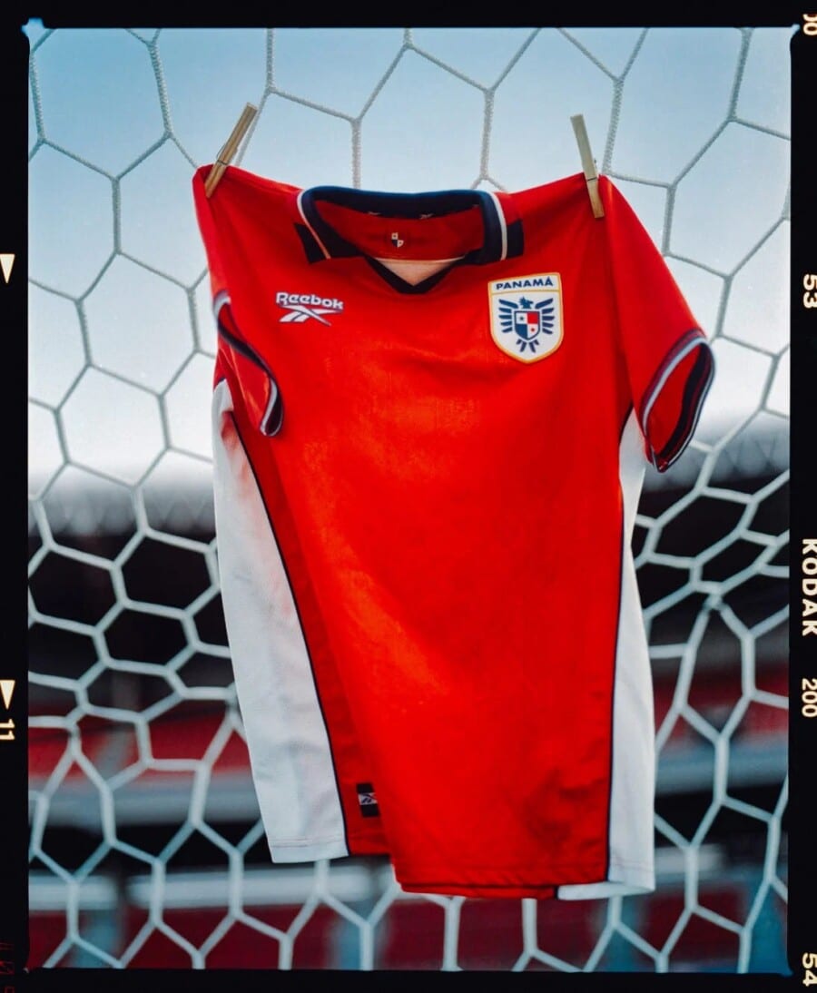 Koszulka reprezentacji panamy na mundial 2026 wisi na siatce zawieszanej na bramce. Sponsorem trykotu jest reebok.