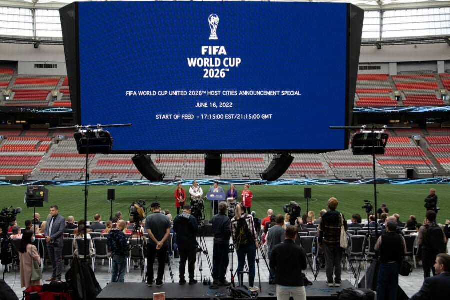 Konferencja prasowa na stadionie z okazji ogłoszenia miast gospodarzy FIFA World Cup 2026 wyświetlana na dużym ekranie.