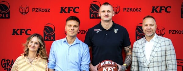 Przedstawiciele Polskiej Ligi Koszykówki, PZKosz i KFC podczas podpisania umowy sponsorskiej na tle czerwonej ścianki z logotypami PLK, PZKosz i KFC.