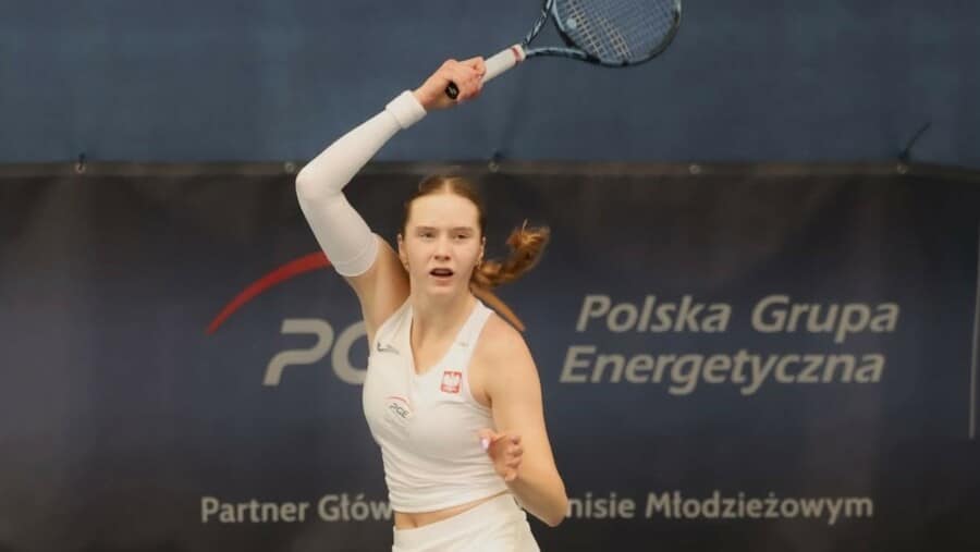 Młoda polska tenisistka Antonina Snochowska podczas zagrania rakietą na tle baneru PGE Polska Grupa Energetyczna.