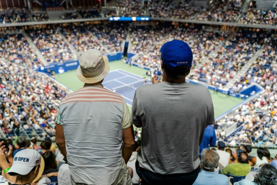 Kibice na wypełnionym po brzegi stadionie US Open oglądają mecz tenisowy z górnych trybun obiektu.