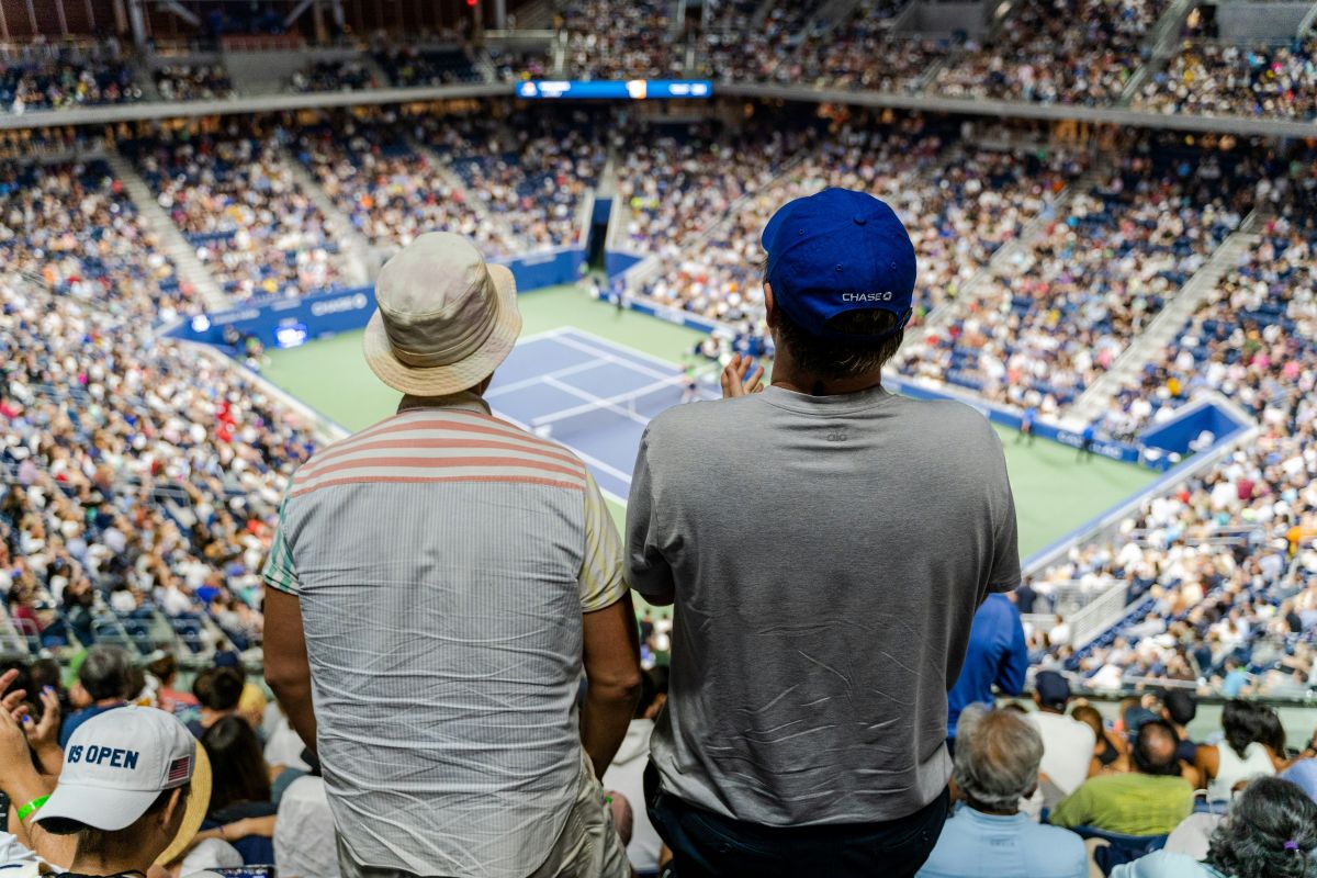 Kibice na wypełnionym po brzegi stadionie US Open oglądają mecz tenisowy z górnych trybun obiektu.