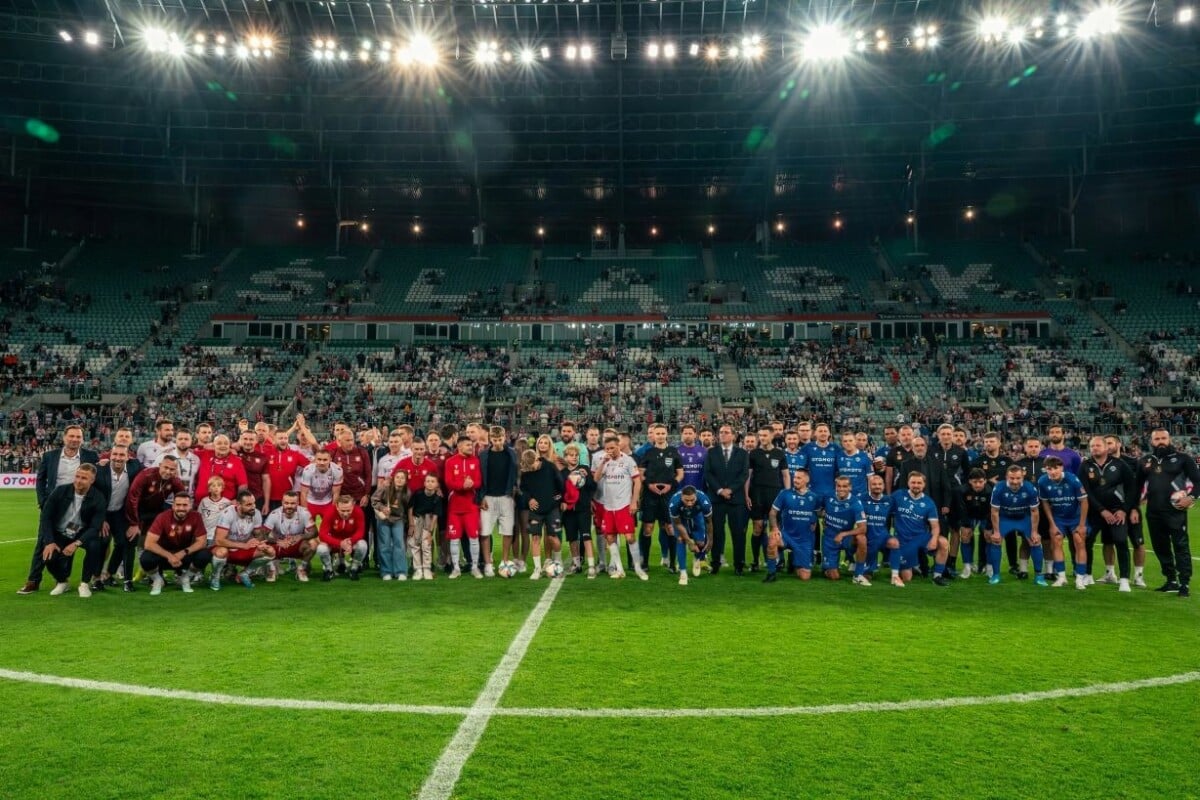 Piłkarze i legendy futbolu pozujący do wspólnego zdjęcia na murawie stadionu Tarczyński Arena we Wrocławiu podczas meczu Ultimate Legends Night.