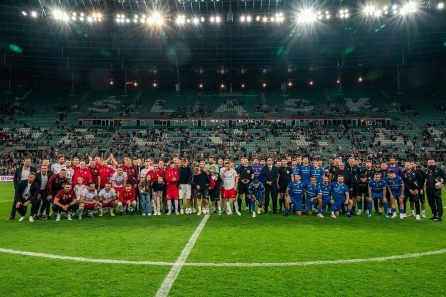Piłkarze i legendy futbolu pozujący do wspólnego zdjęcia na murawie stadionu Tarczyński Arena we Wrocławiu podczas meczu Ultimate Legends Night.