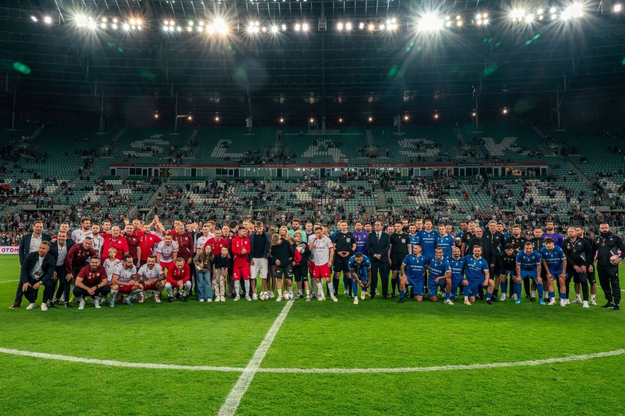 Piłkarze i legendy futbolu pozujący do wspólnego zdjęcia na murawie stadionu Tarczyński Arena we Wrocławiu podczas meczu Ultimate Legends Night.